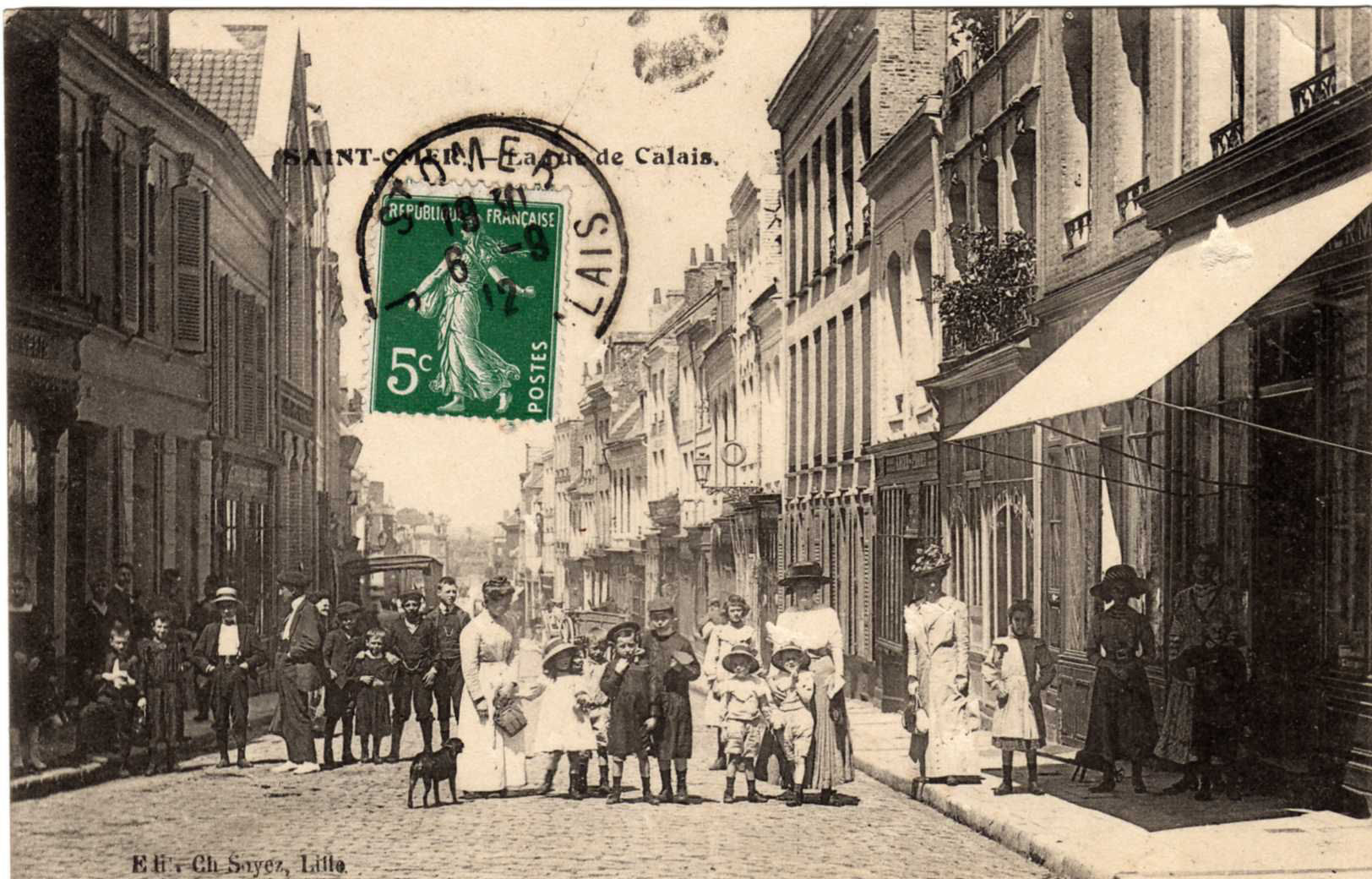 On peut voir les passants qui étaient nombreux à poser pour le photographe,les dames sont en longues robes et chapeaux comme c'était la mode à cette époque.